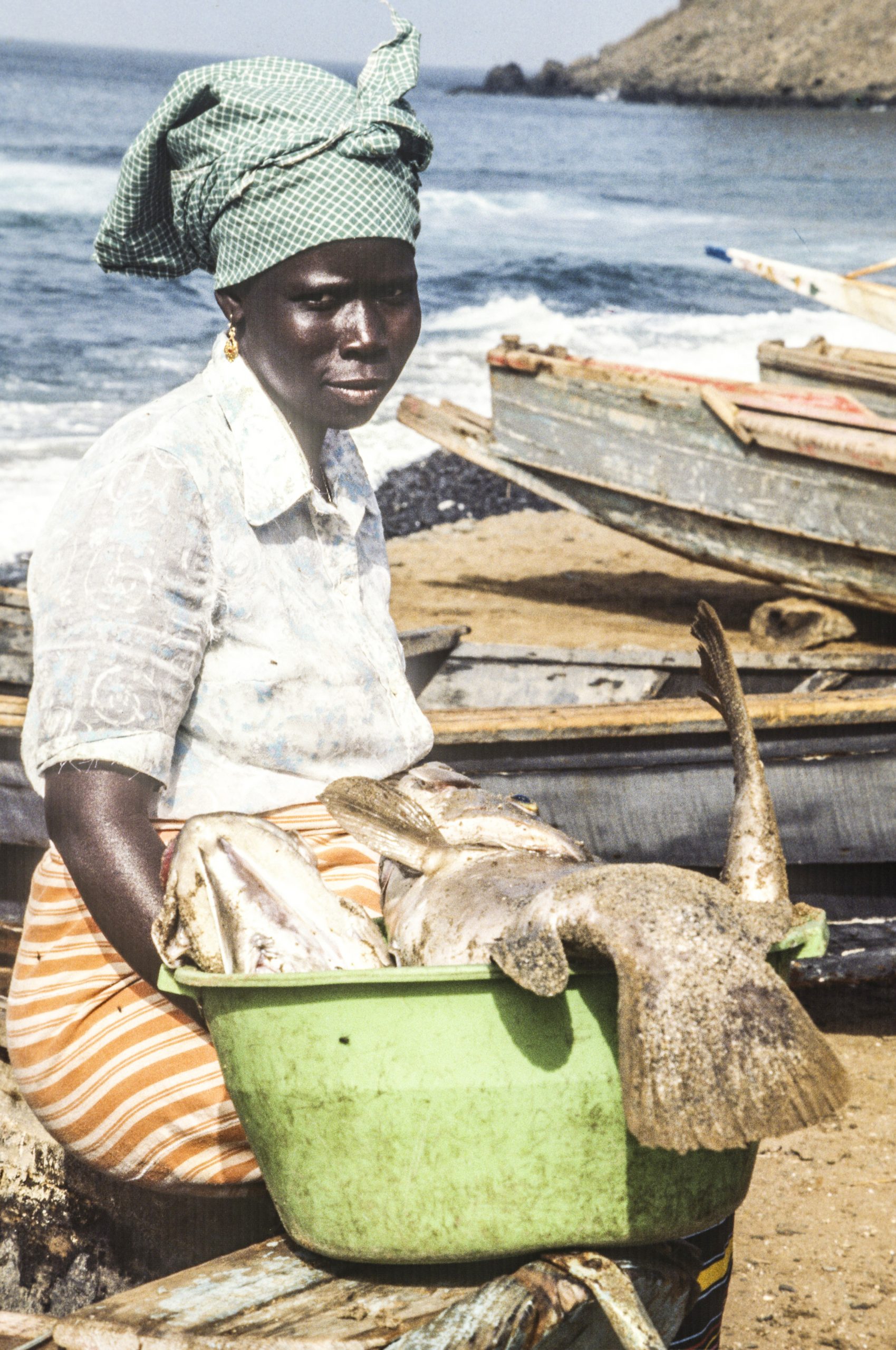 A woman sits on a canoe beached at Ouakam, a small fishing village near Dakar, Senegal
